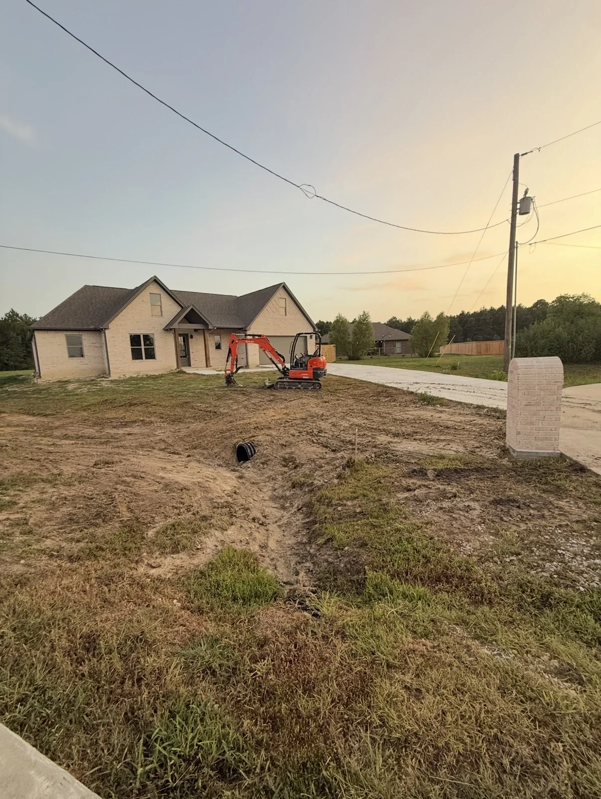 Mini excavator performing drainage and grading work at a home